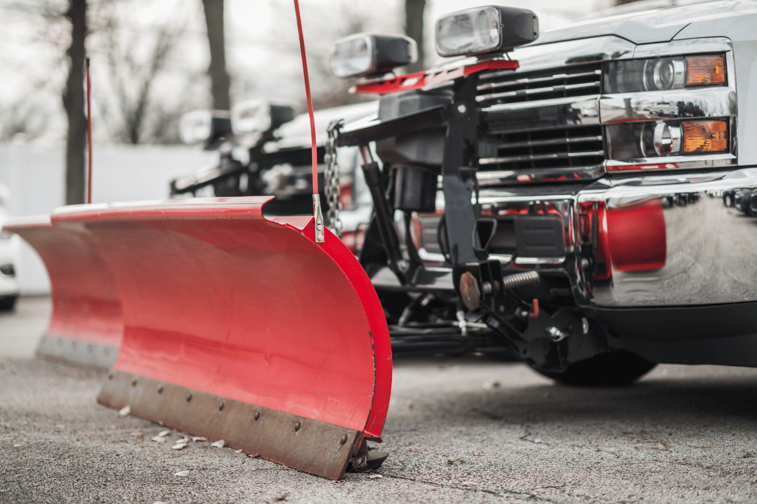 Red snowplow blade attached to a truck parked on a road