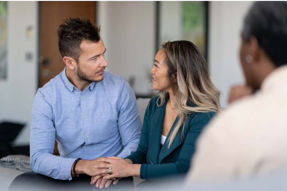 A picture of a couple looking at each other while holding hands .