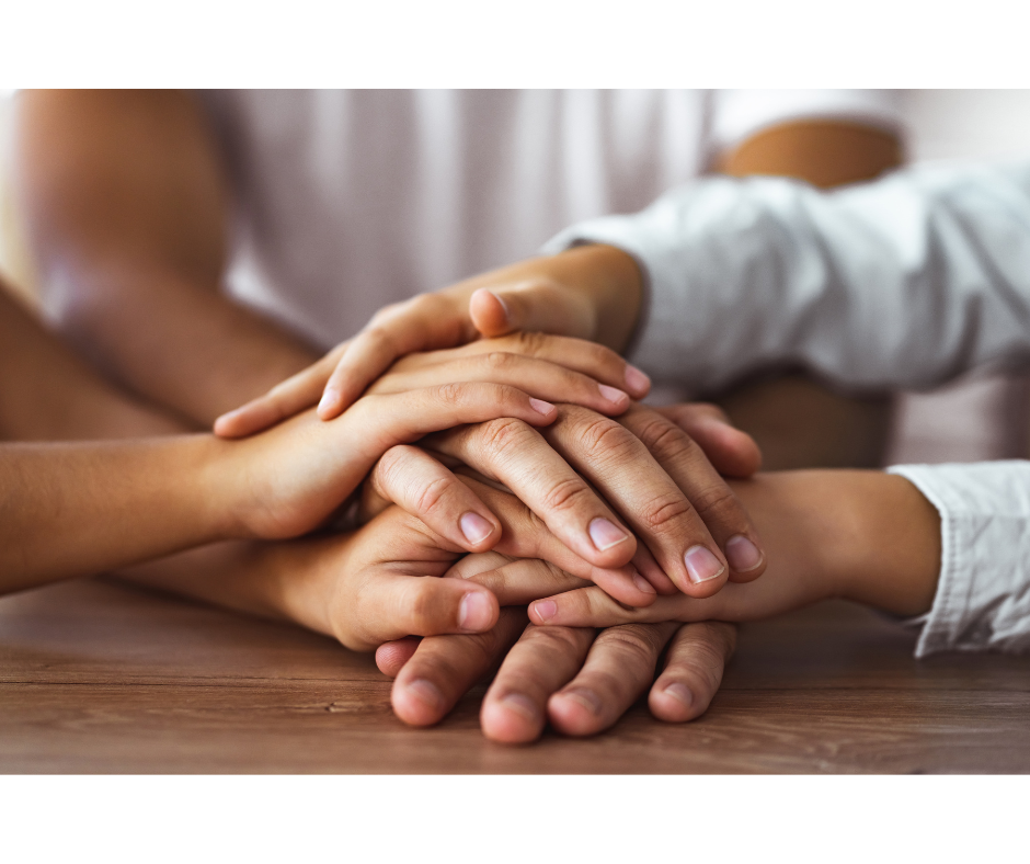 Hands stacked in a pile, symbolizing teamwork and collaboration.