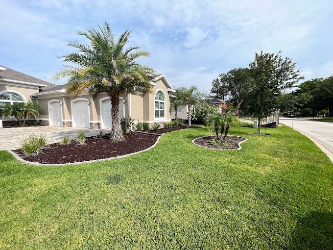 Exterior view of a beige house with palm trees, green grass, and a sunny sky.