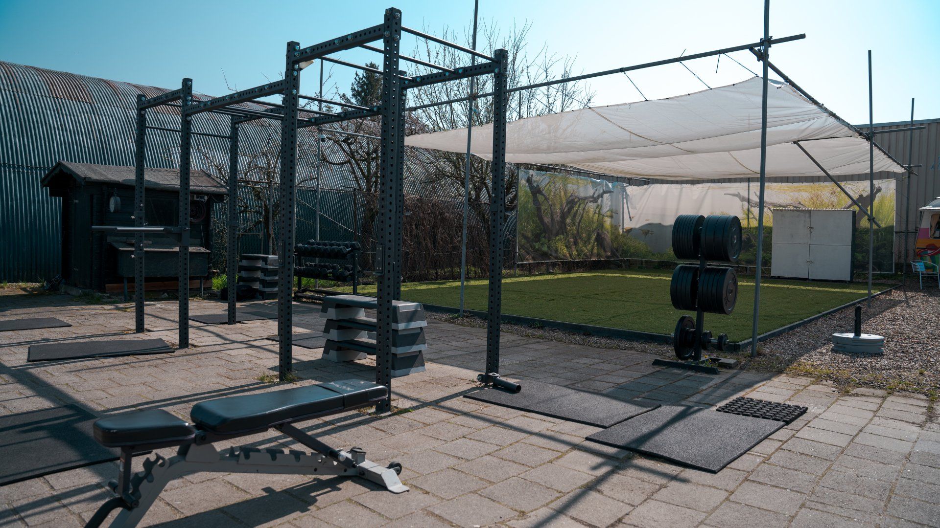 Een rij fitnessapparatuur staat op een trottoir voor een gebouw.