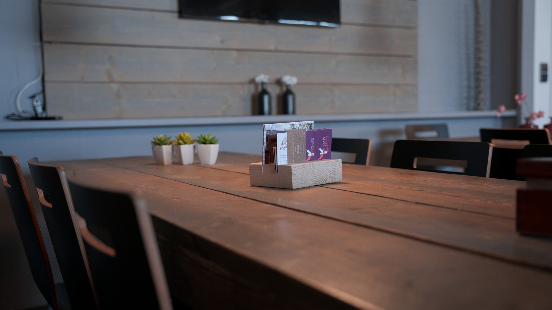 Een lange houten tafel met een zout- en peperstrooier erop.