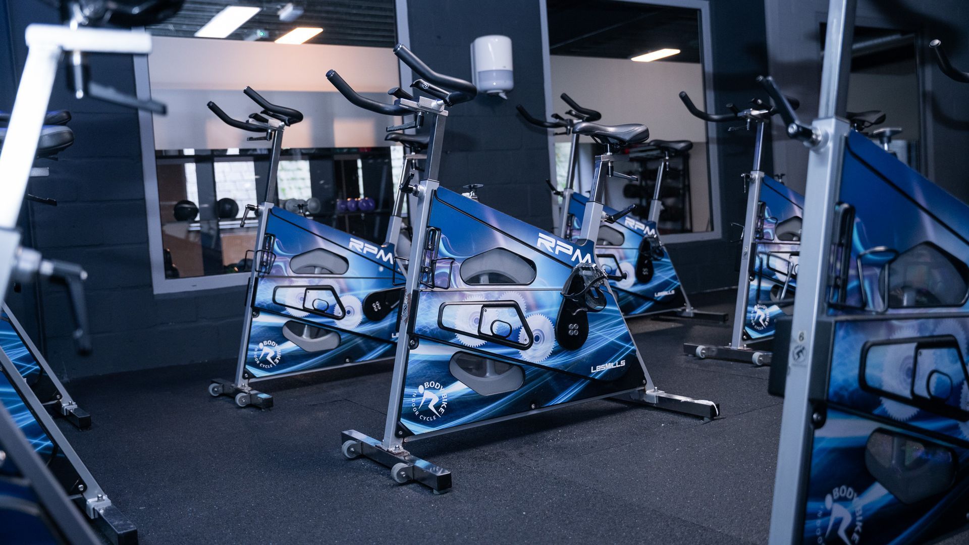 In een sportschool staat een rij hometrainers opgesteld.