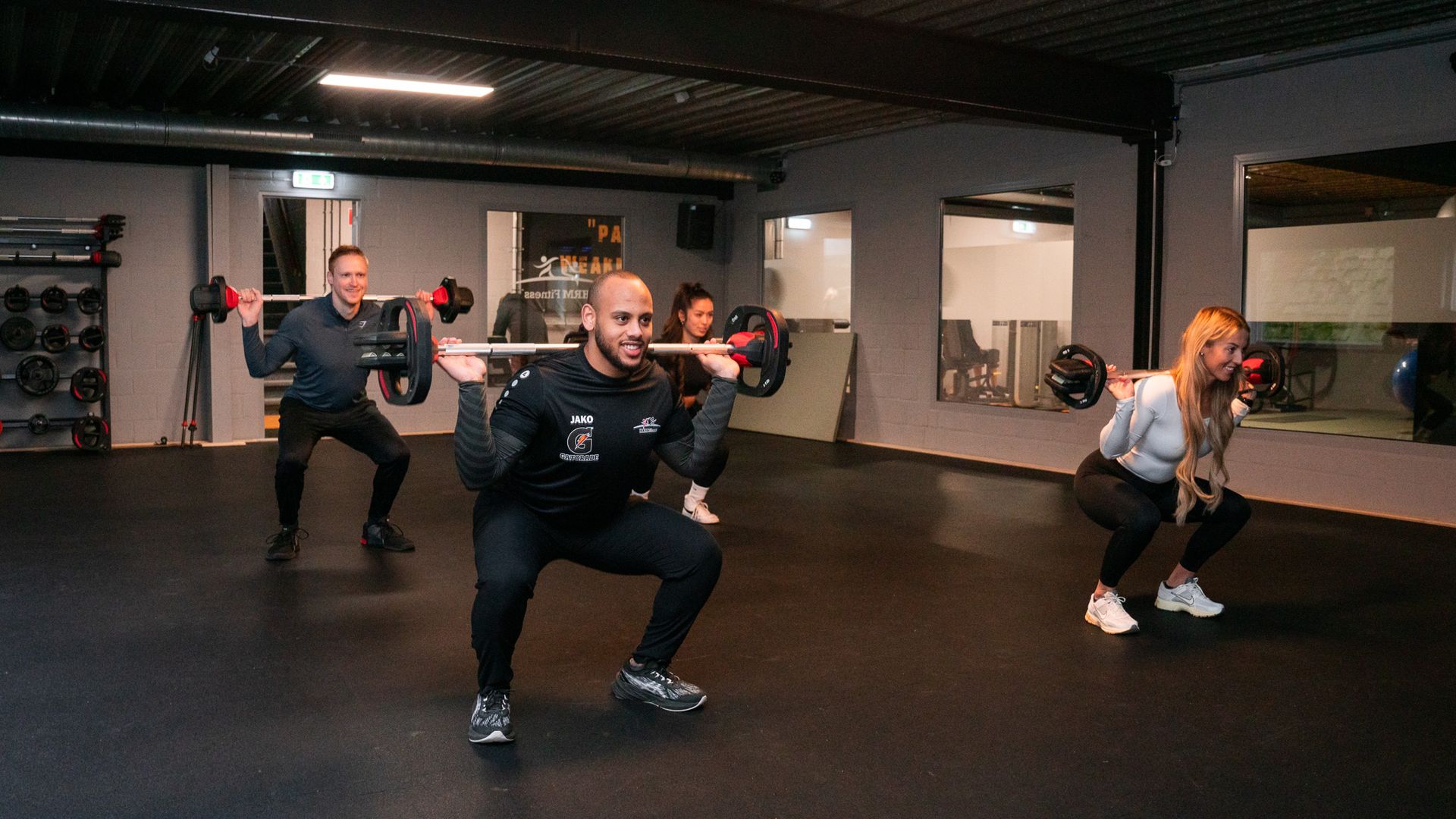Een grote lege dansstudio met een houten vloer en spiegels.