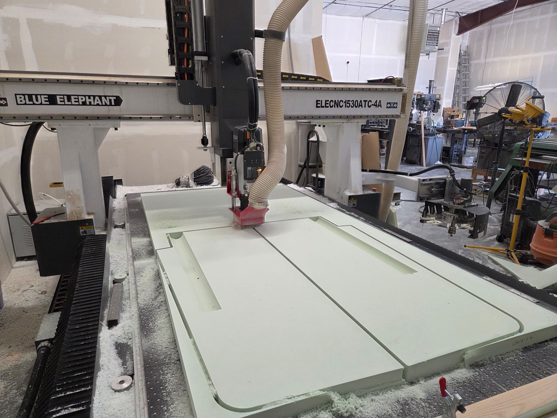 Industrial robot cutting a large white panel in a workshop
