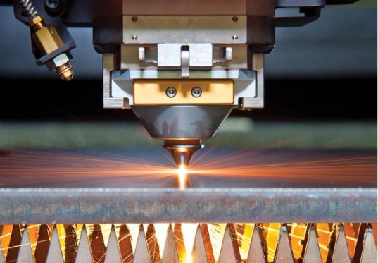Laser cutting metal sheet with a bright orange beam and sparks from a cutting machine