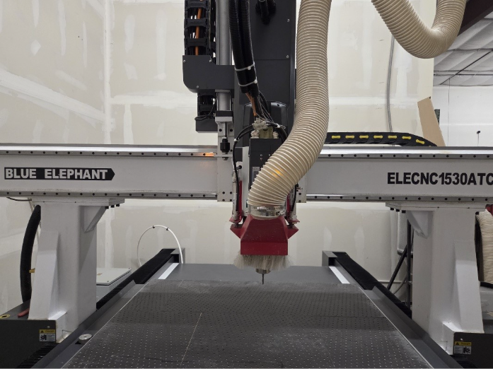 Large blue CNC router with red cutting head in a workshop