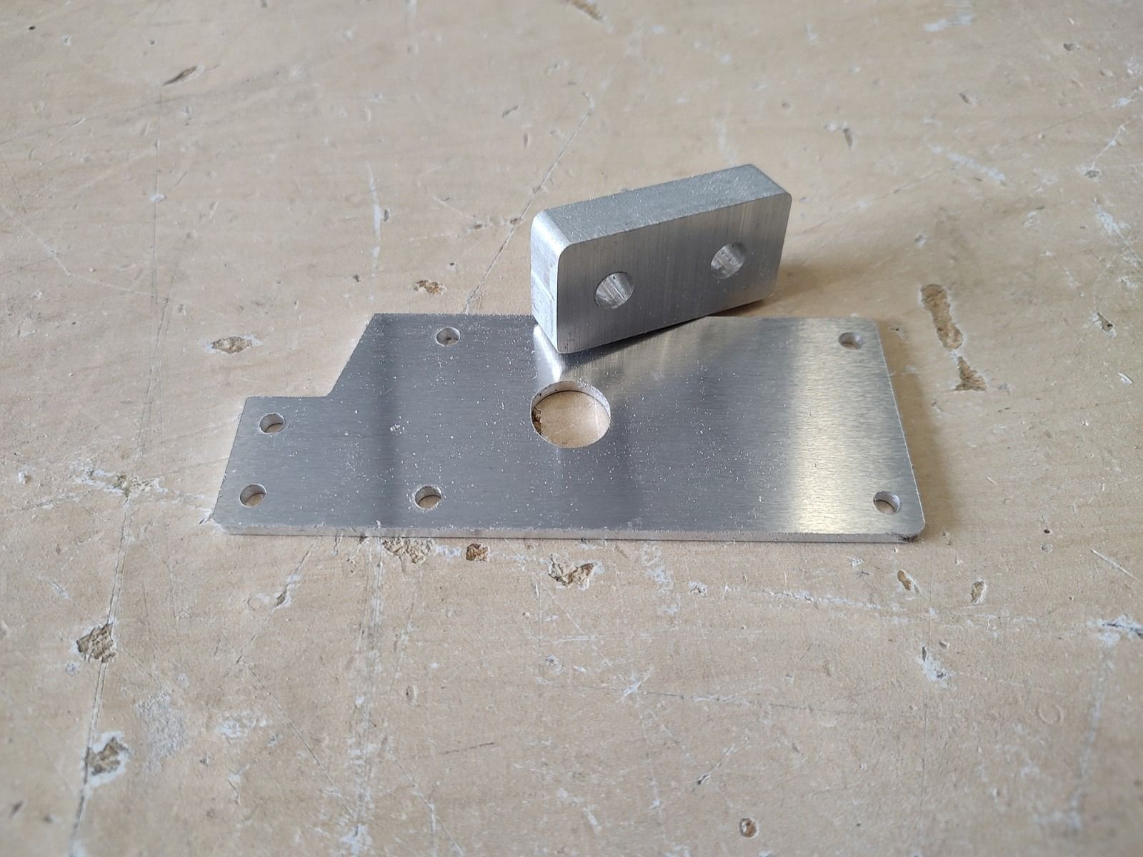 Small metal bracket with a pivoting plate resting on a workbench.