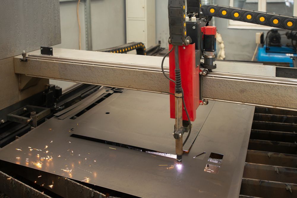 Laser cutting machine cutting a metal sheet, with sparks flying in an industrial workshop.