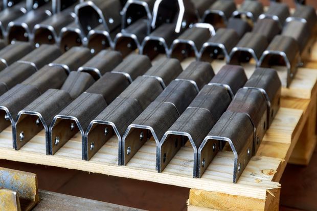Rows of dark metal U-shaped brackets stacked on a wooden pallet