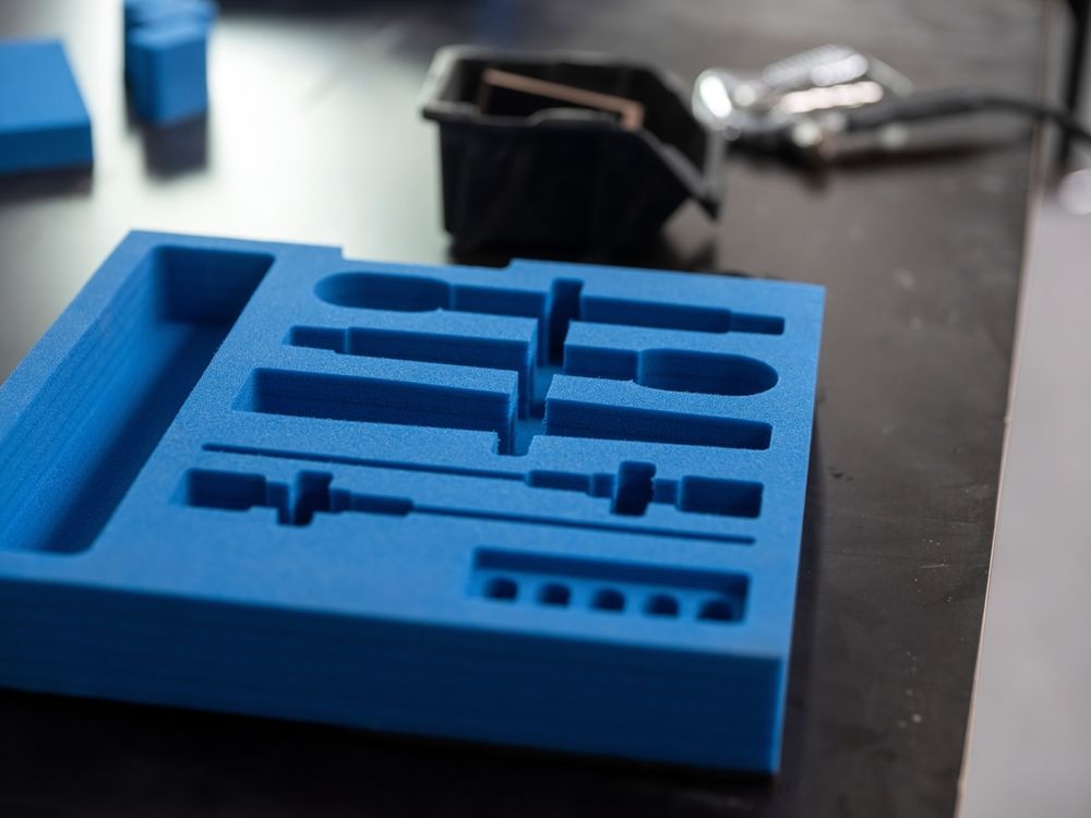 Blue 3D-printed tray with assorted tool-shaped cutouts on a workbench