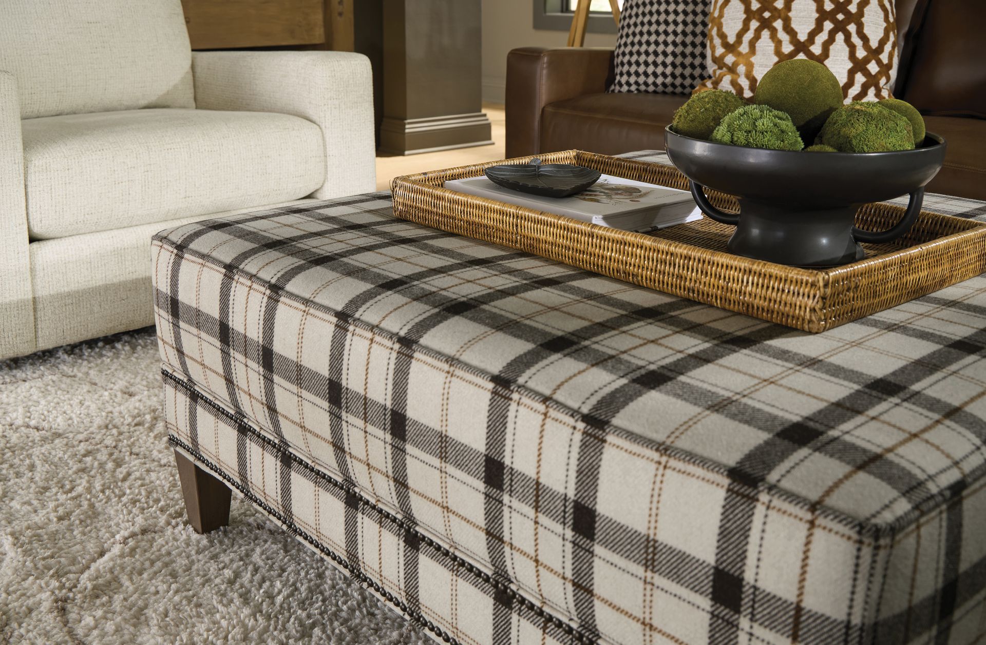 Plaid ottoman with a tray holding decorative balls, in a living room setting.
