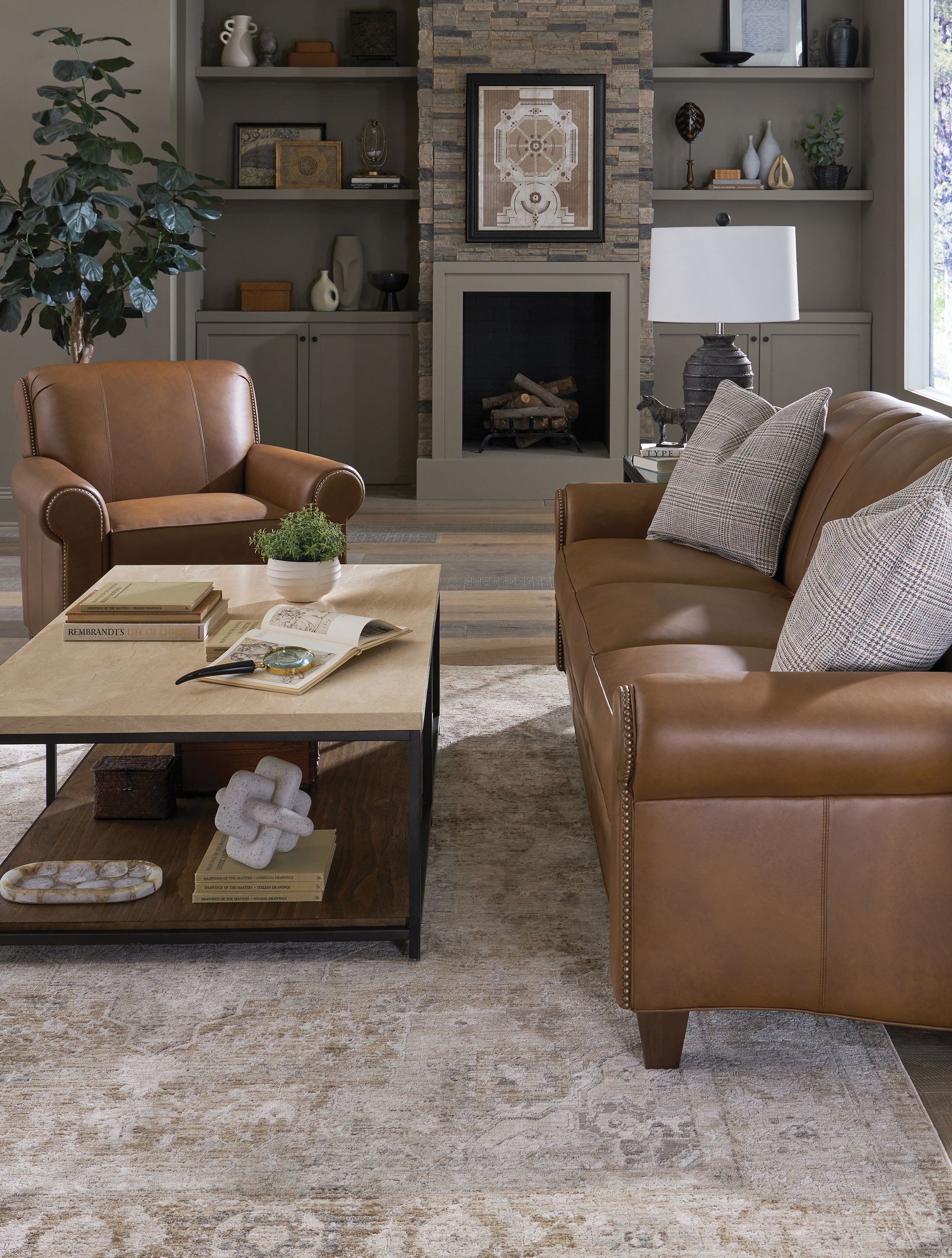 Living room with leather furniture, fireplace, and coffee table on a patterned rug.
