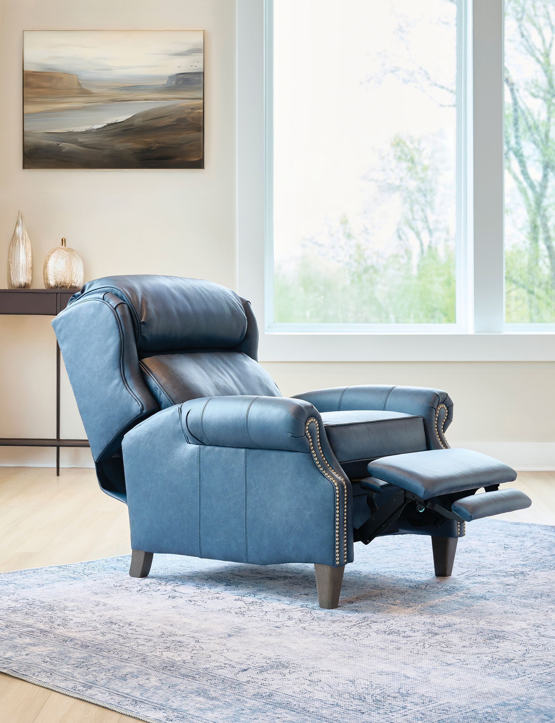 Blue recliner with footrest extended, in a room with a window and rug.