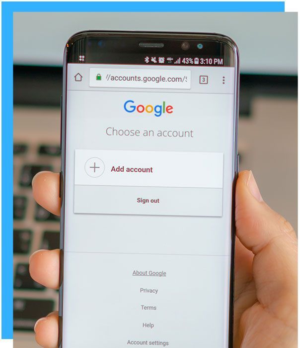 Hand holding a smartphone displaying the Google account selection screen.