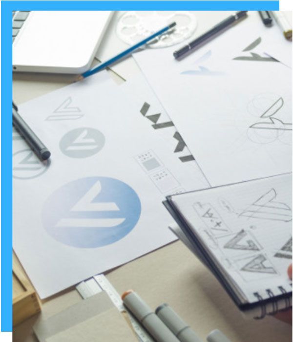 Logo design process with sketches, markers, and laptop.