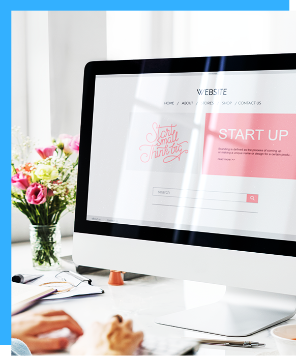 Computer screen displaying a startup website, beside flowers and a person's hand typing.