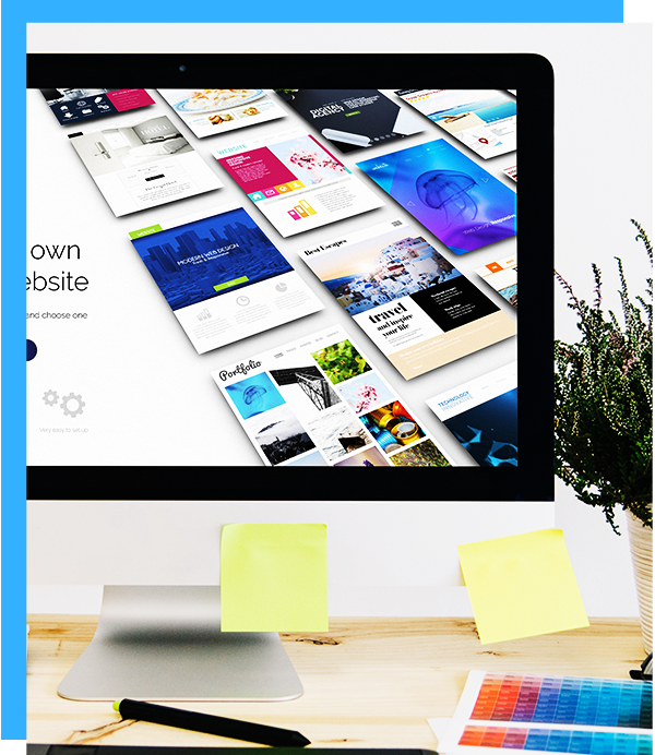Desktop computer displaying website templates with sticky notes and color swatches on desk.