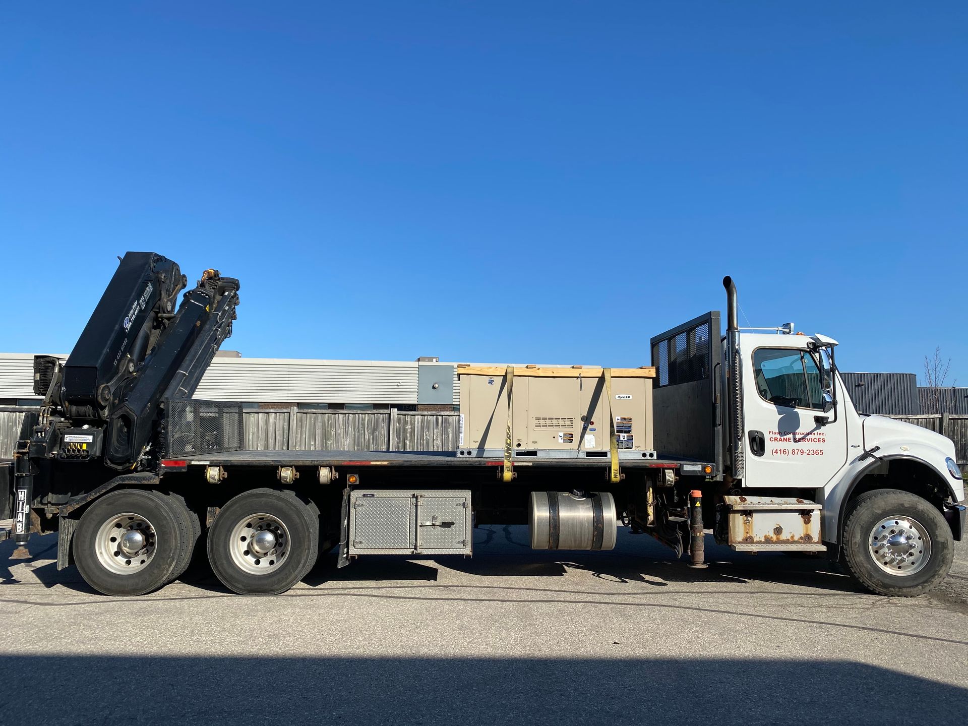 A large truck with a crane on the back is parked on the side of the road.