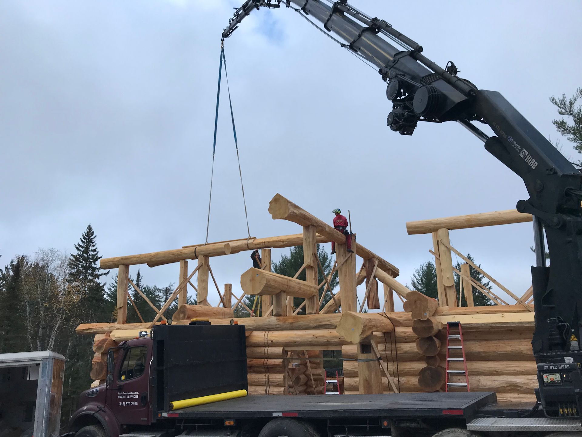 A truck with a crane attached to it is carrying logs.