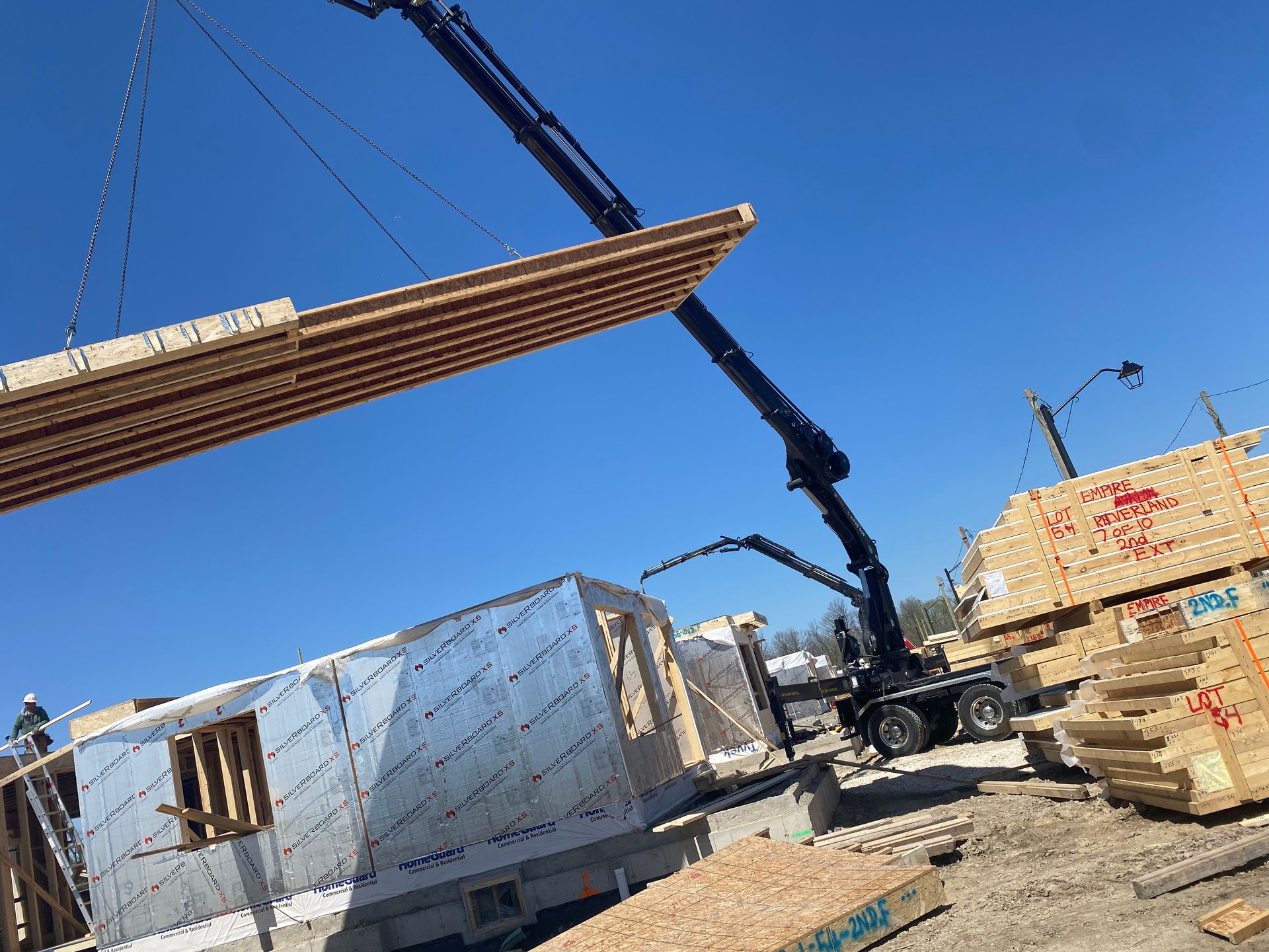 A crane is lifting a piece of wood over a building under construction.