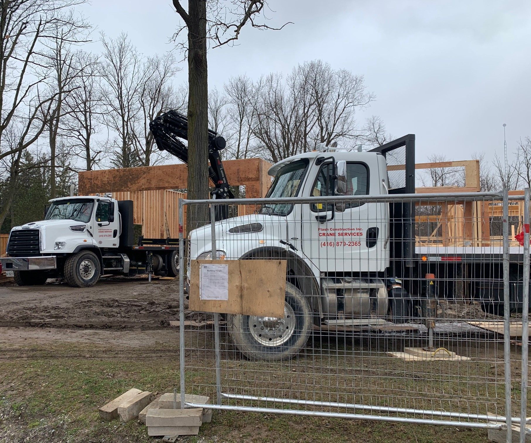A construction truck is parked in front of a fence at a construction site.