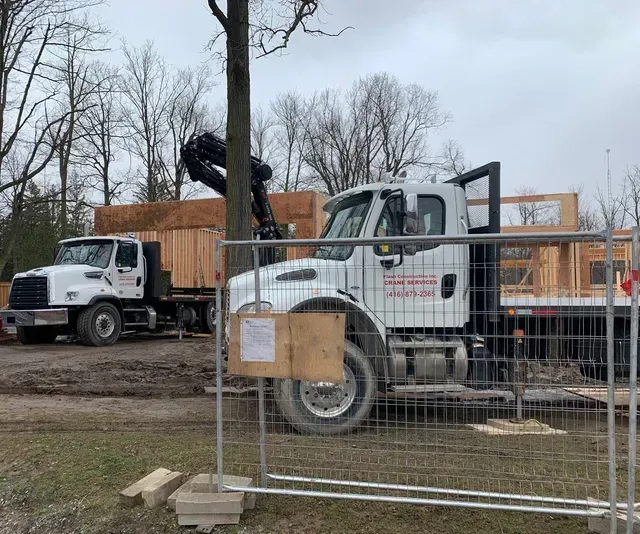 A construction truck is parked in front of a fence at a construction site.