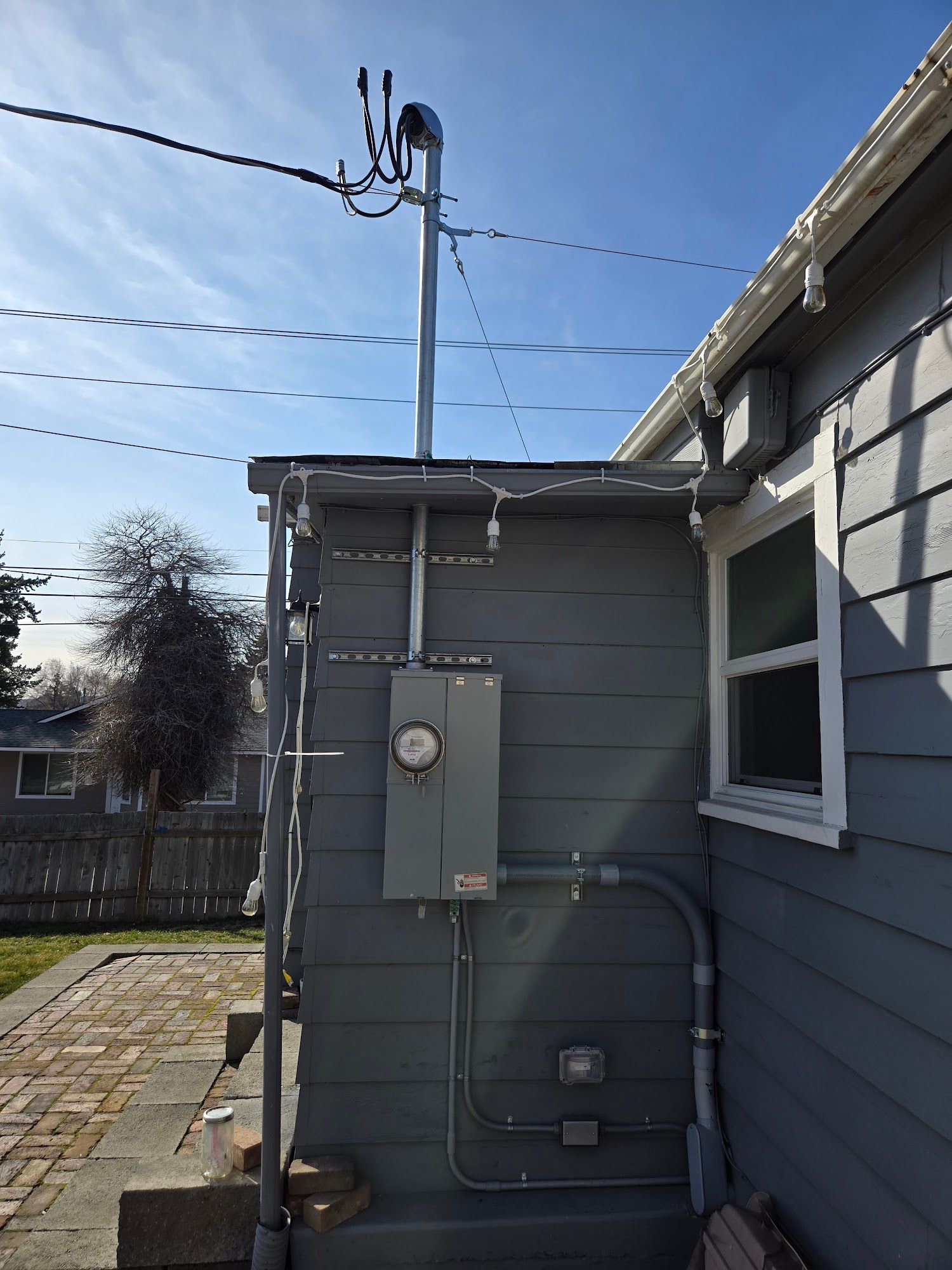 A white house with a green roof has a electrical box on the side of it.