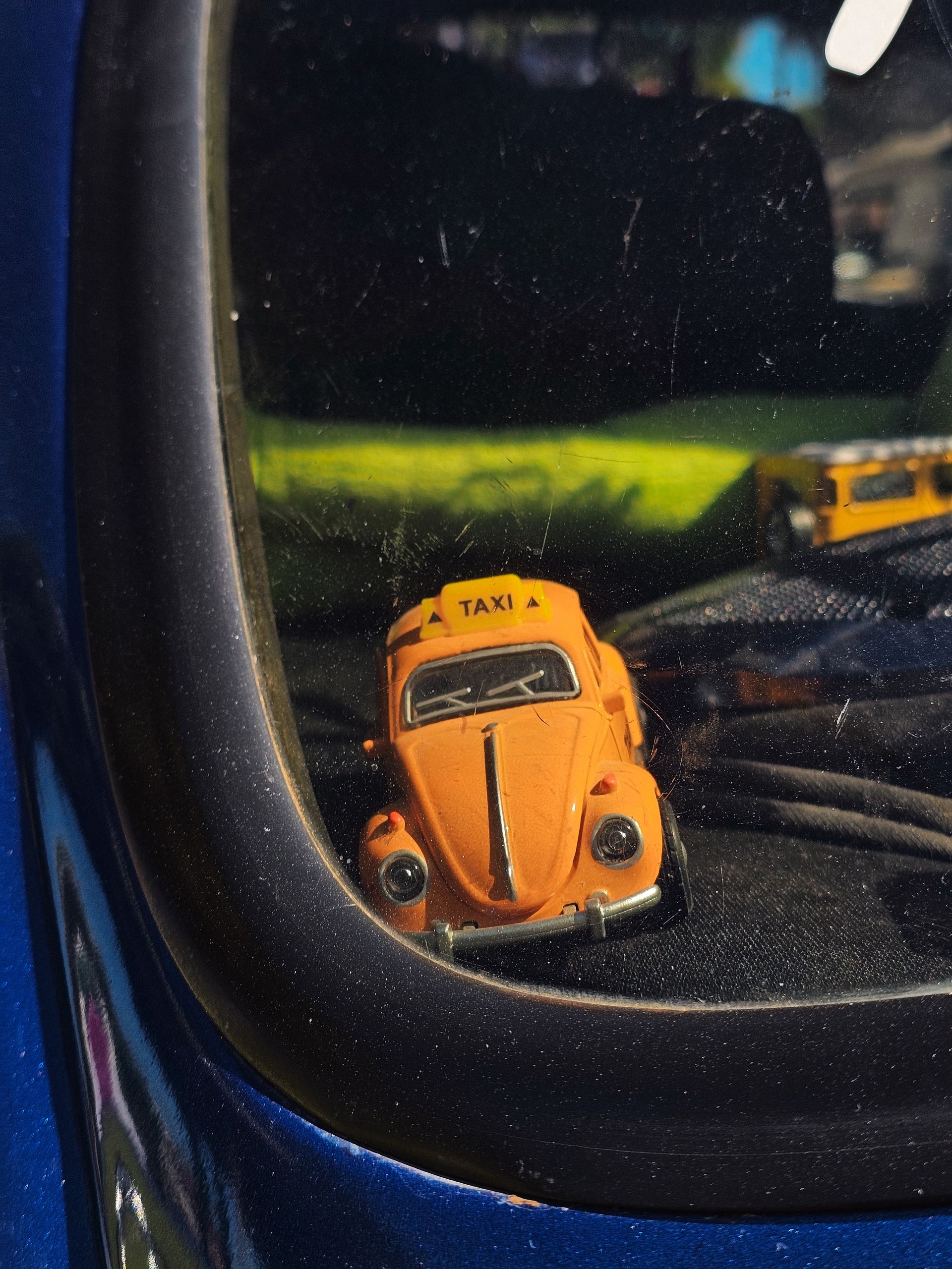 Carrinho de brinquedo laranja em uma vitrine escura com frente de vidro reflexivo.