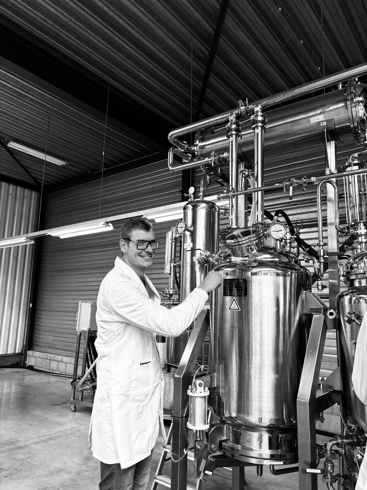 A team member playfully posing next to a vanilla extraction machine at GFE Group.