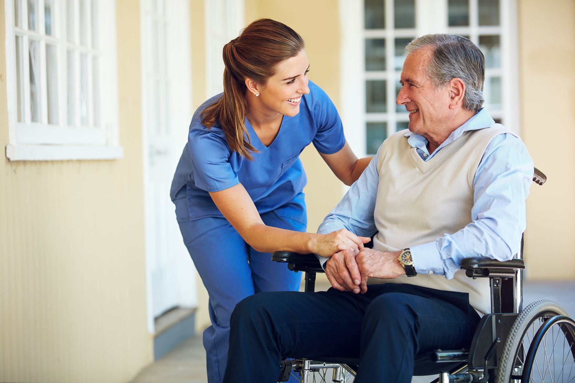 Elderly man sitting in a wheelchair beside a skilled nurse