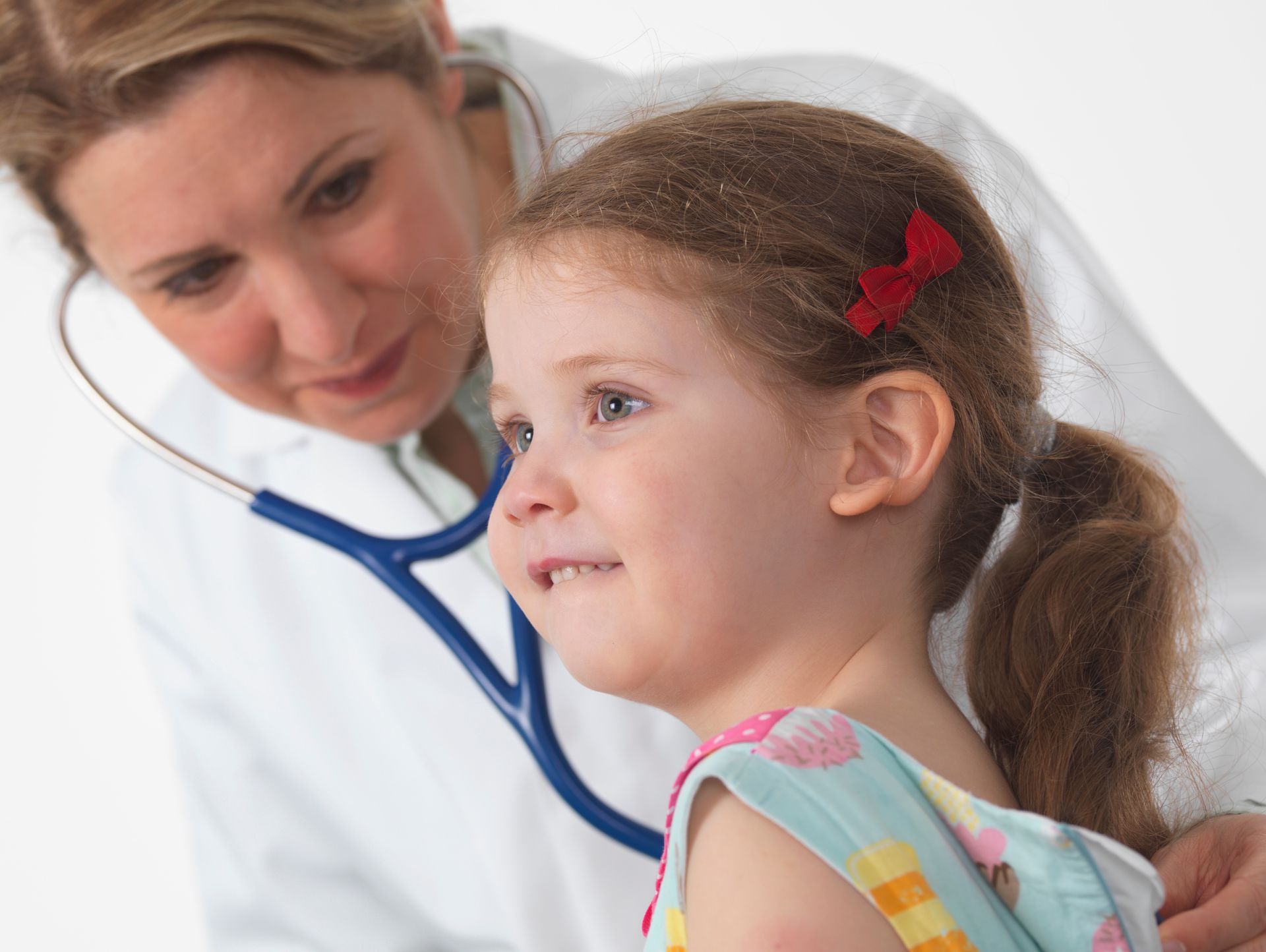 Pediatric doctor using a stethoscope to check a child’s heart and lungs during home care visit