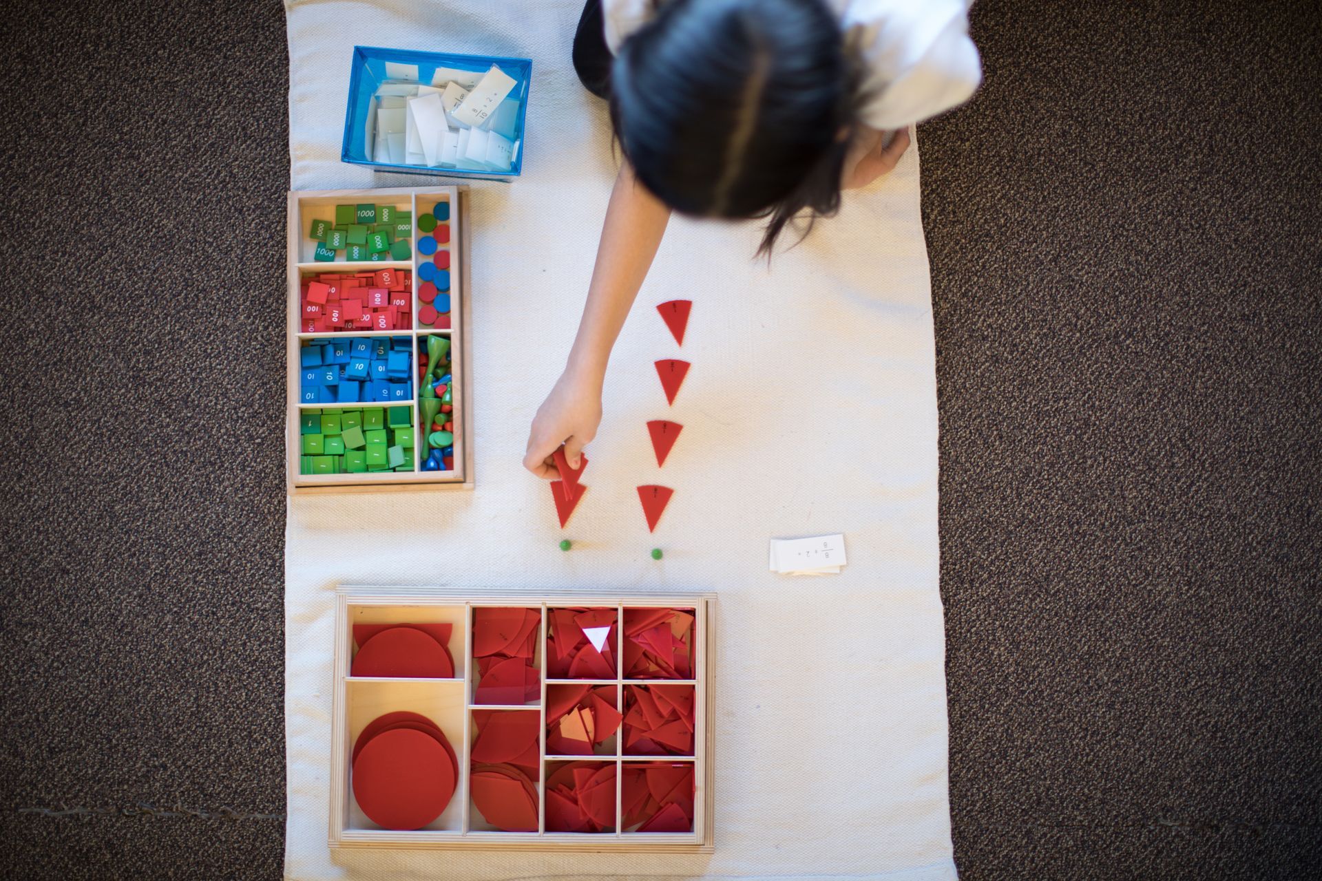 Child working with the stamp game and fractions materials in a Montessori classroom