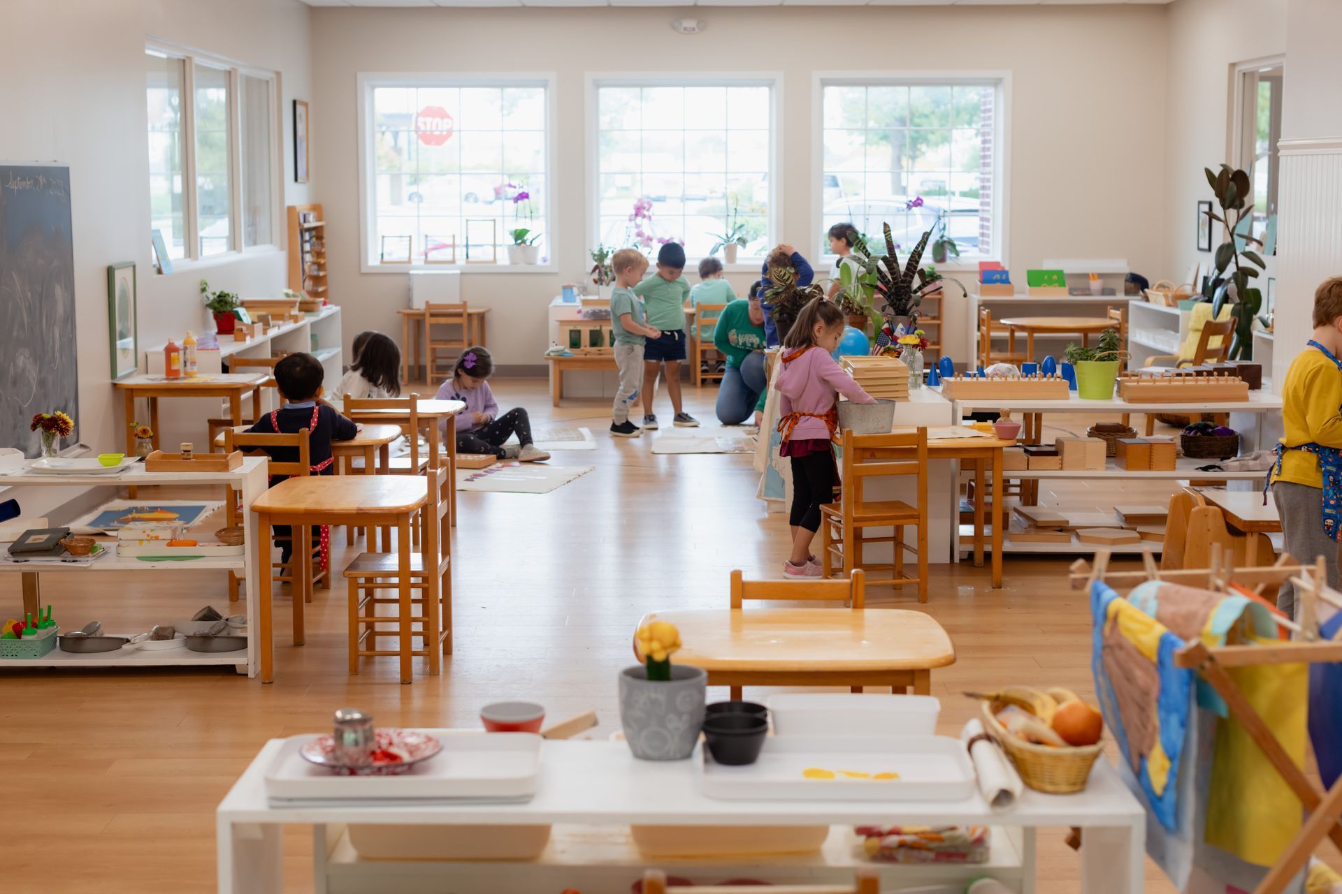 Children painting and working at tables in a bright Montessori classroom