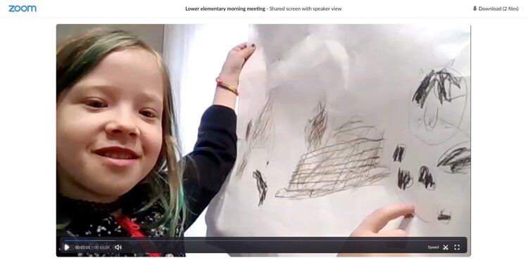 Montessori Child smiling beside a whiteboard, pointing at a drawing in black marker