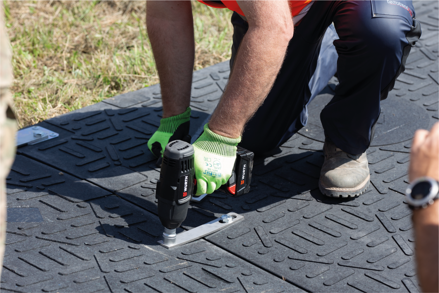 Un hombre está usando un taladro para hacer un agujero en una alfombra de Isotrack.