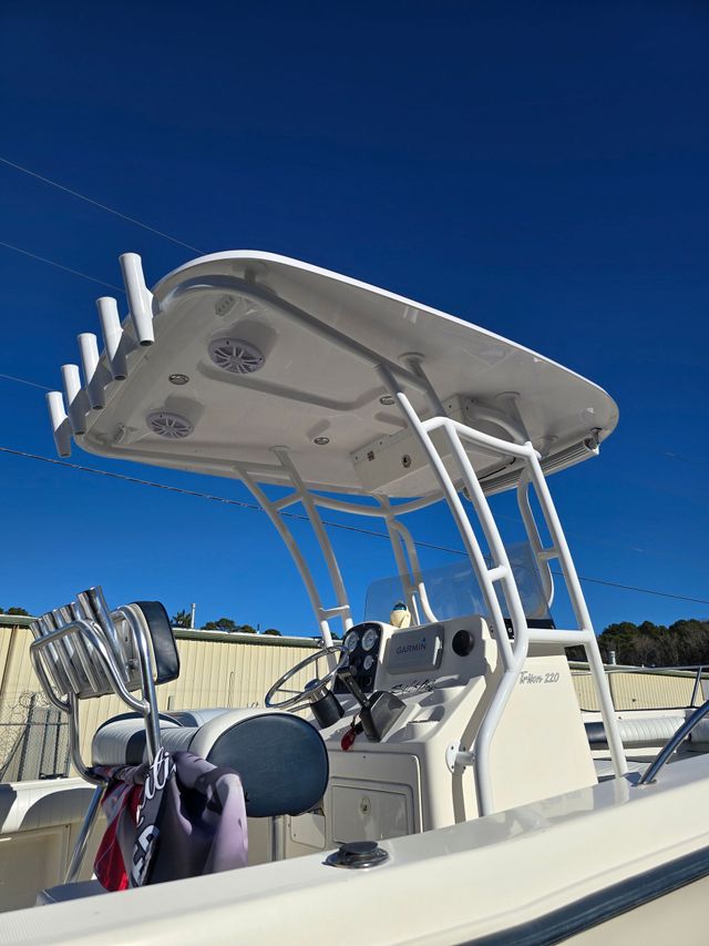 Boat cockpit under a canopy at a marina, with fishing rods and calm water at sunset.