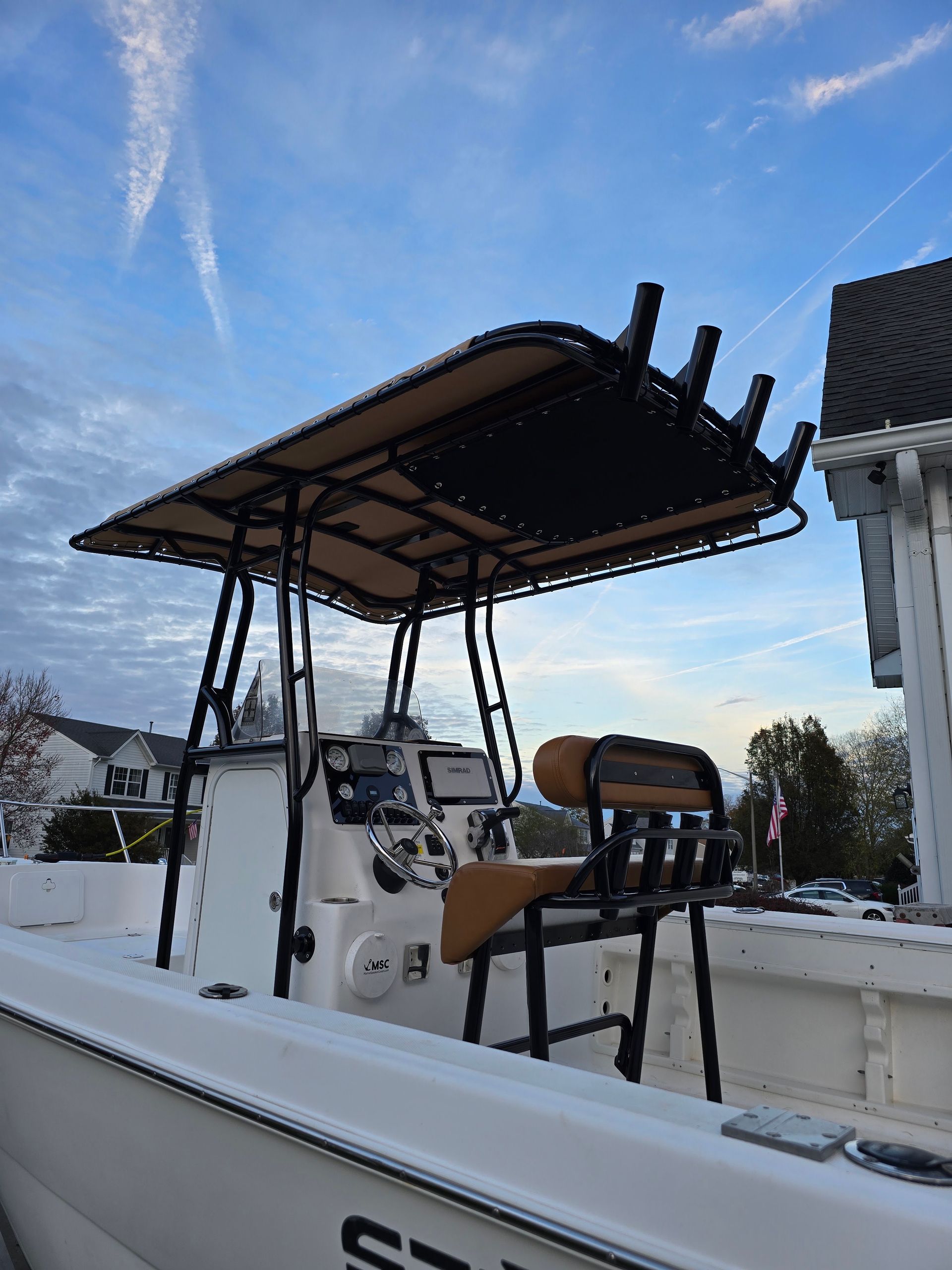 White boat with a black canopy and chairs docked beside a snowy waterfront under a blue sky