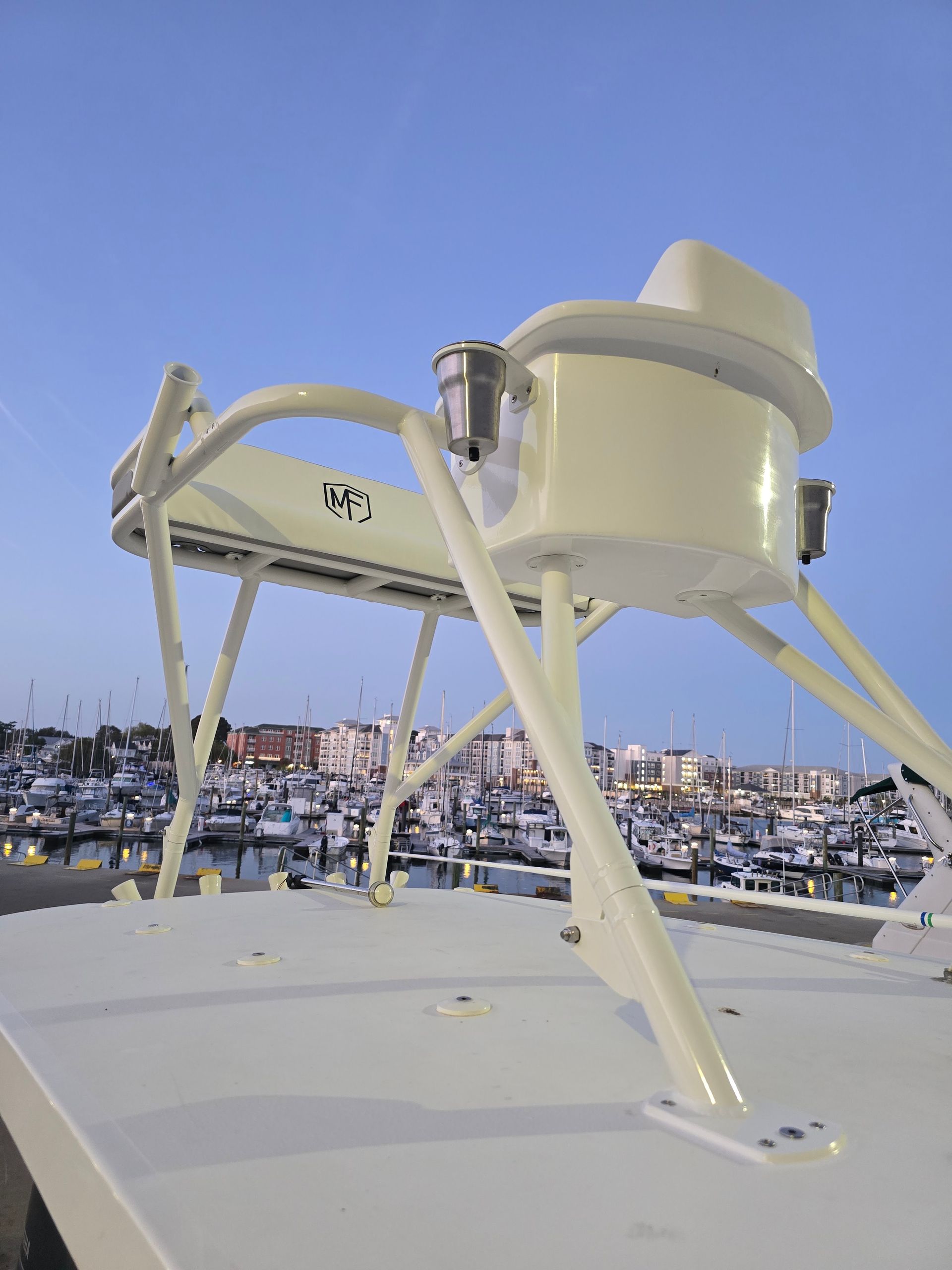 White marine radar dome on a boat roof, overlooking a harbor full of boats at dusk