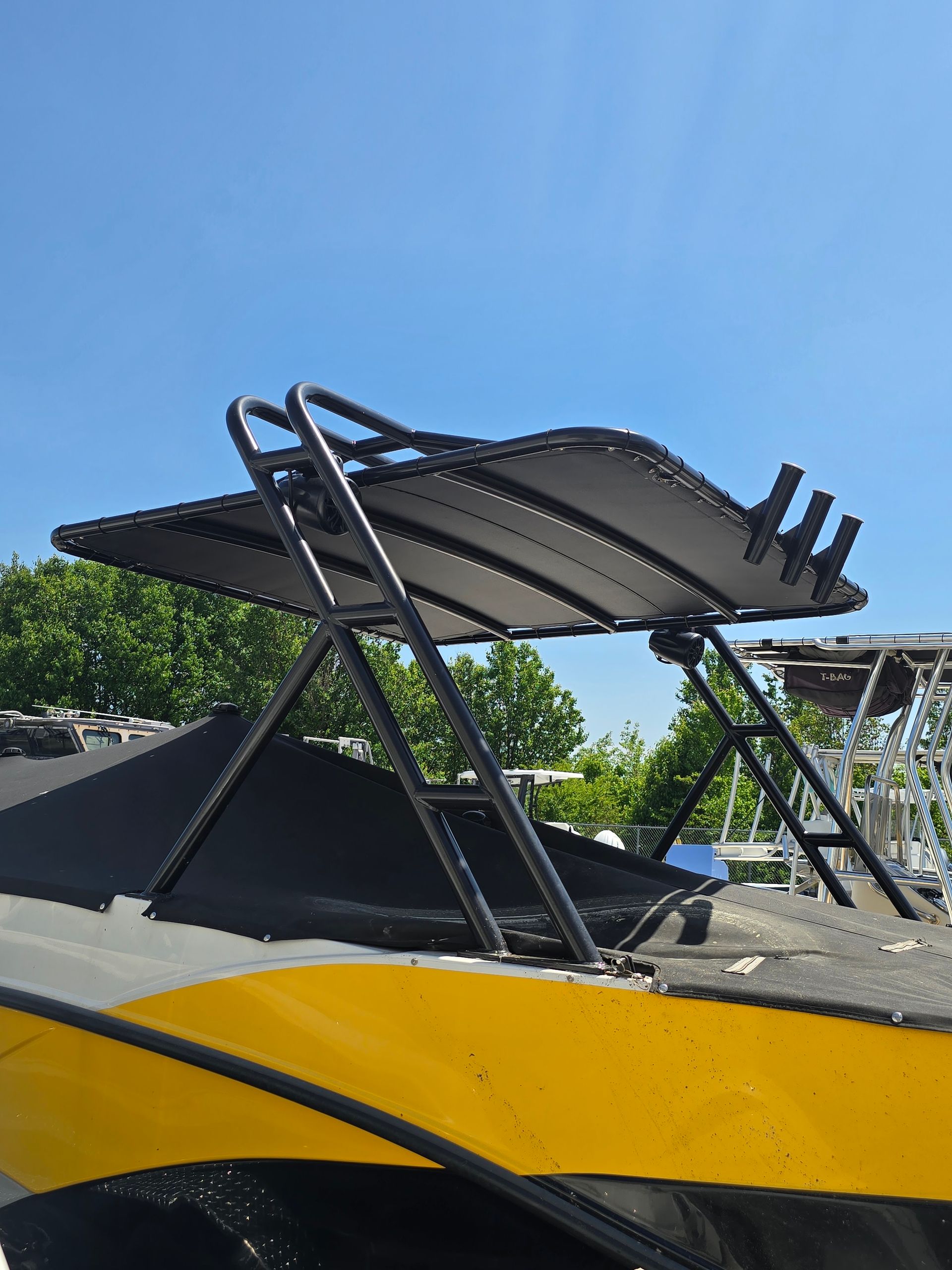 Black metal car roof rack/awning mounted on a yellow vehicle under a blue sky