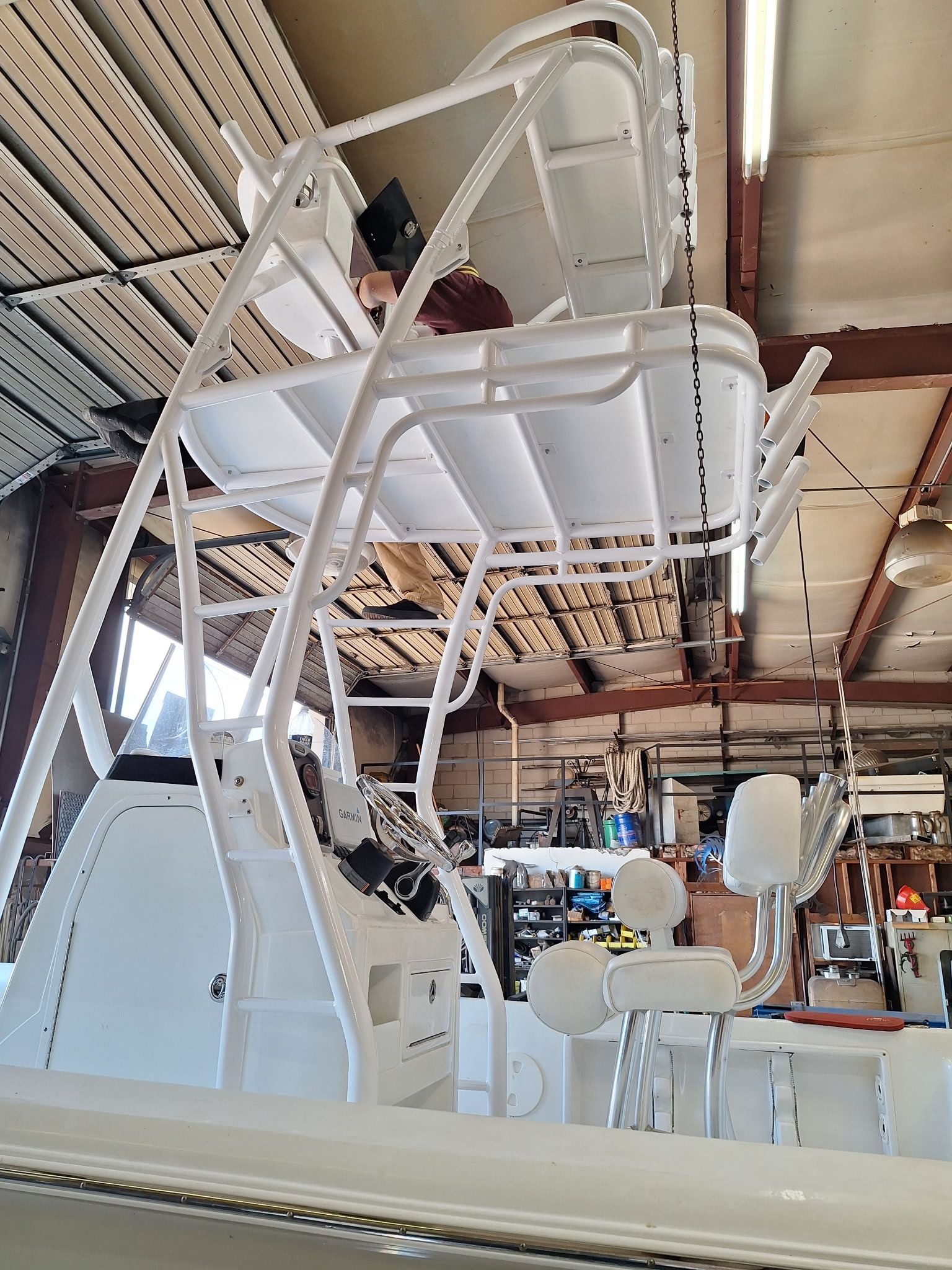 White metal amusement ride in a warehouse, with a person seated inside the suspended car.