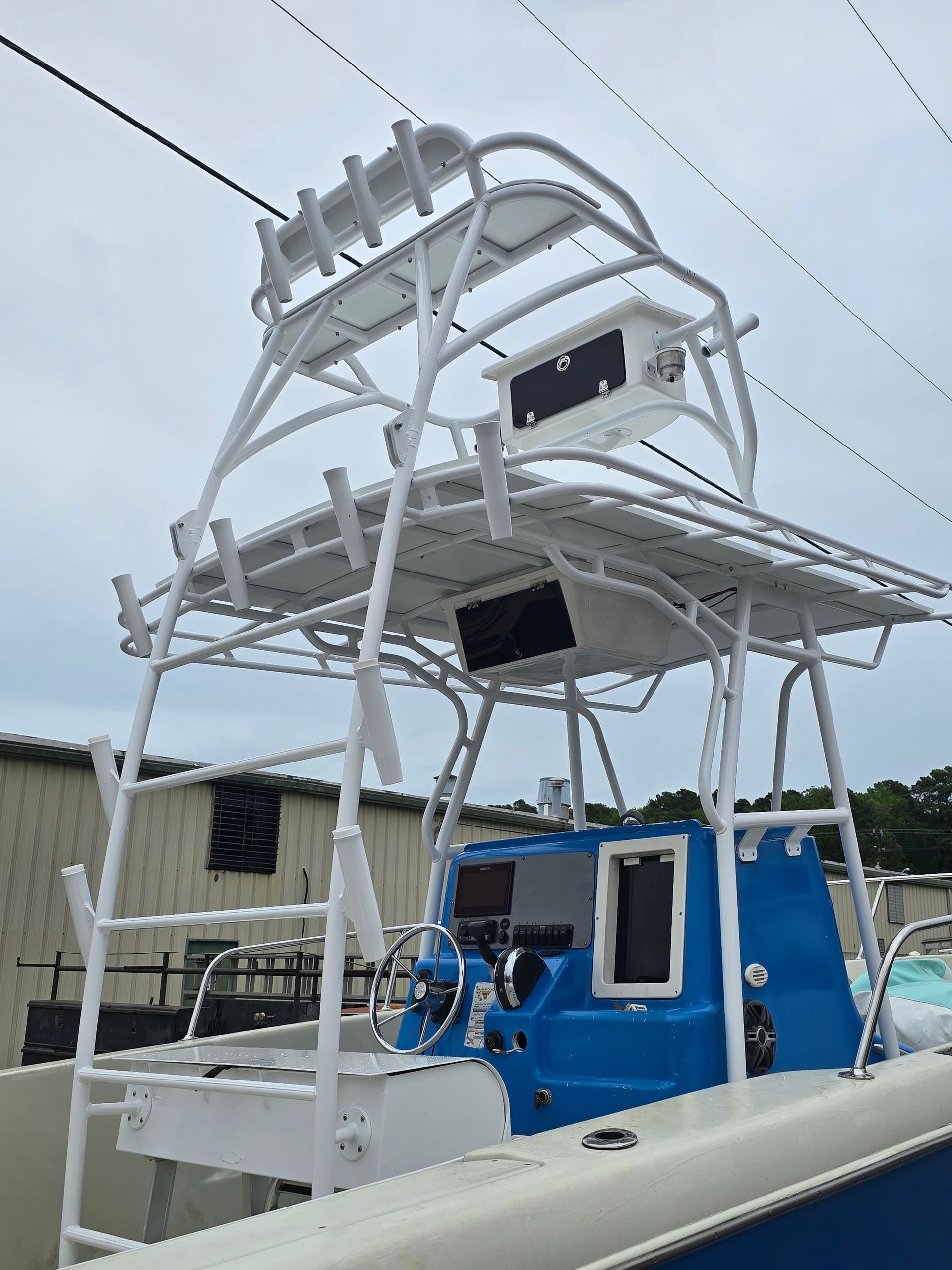 Blue boat with white tower and equipment on deck, docked under an overcast sky
