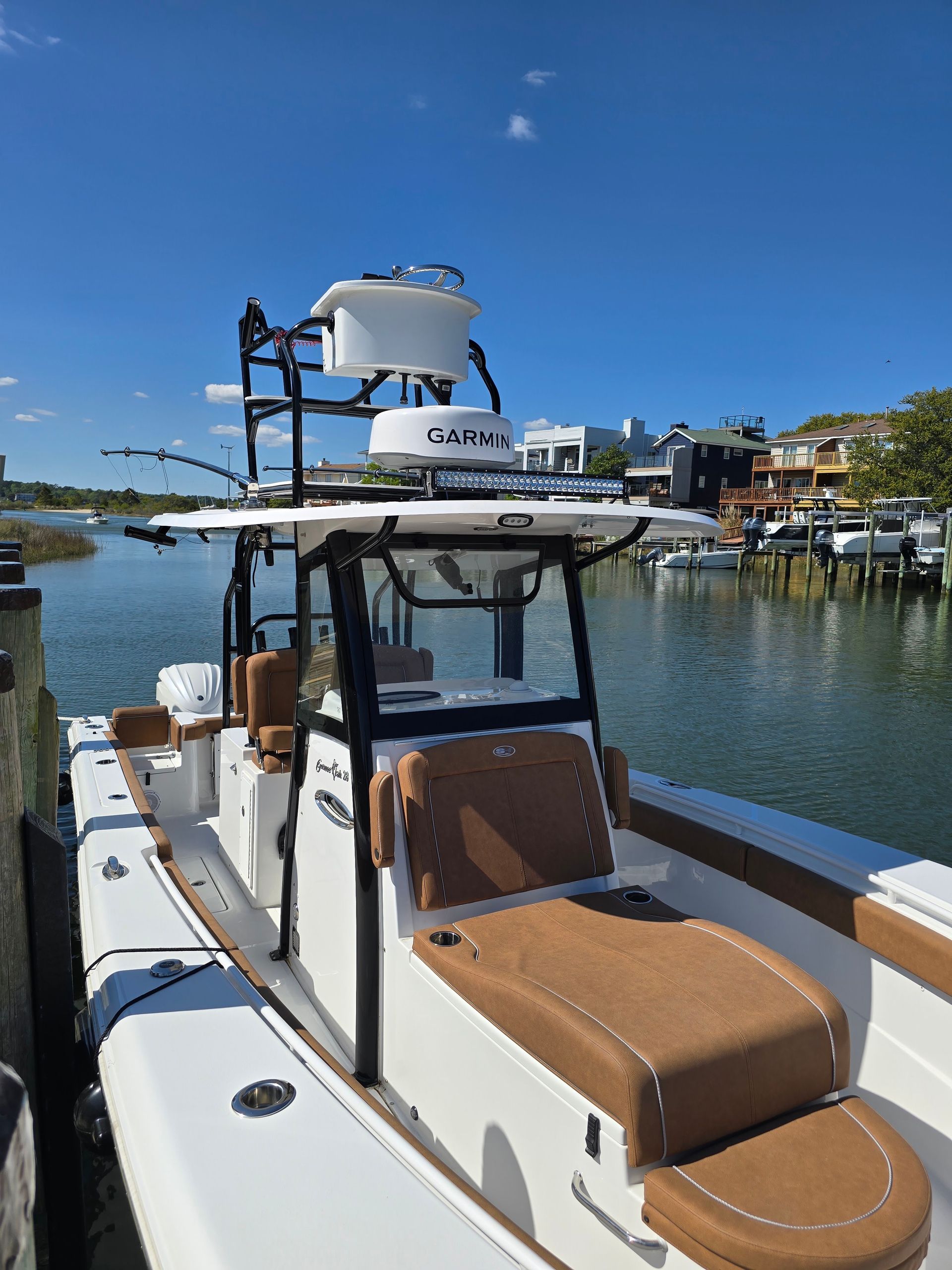 White boat with tan seats docked in a marina under a clear blue sky