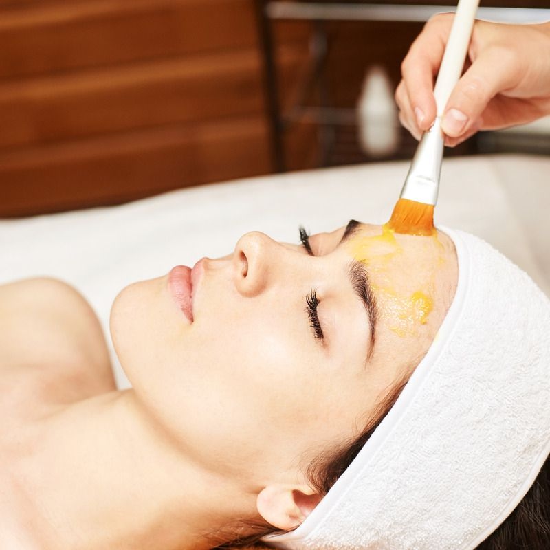 Woman receiving facial treatment, application of a mask.