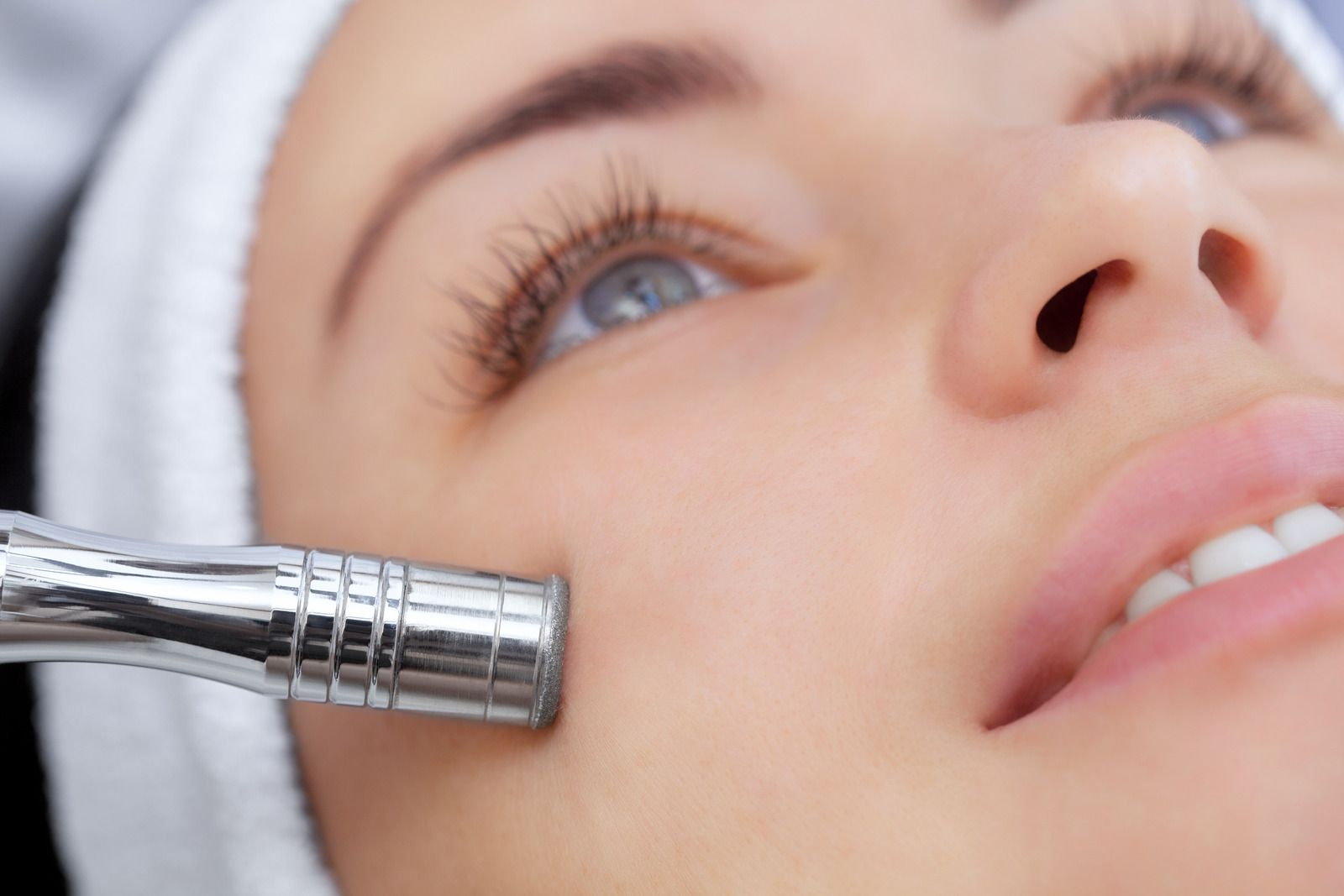 Woman receiving a facial treatment with a diamond-tipped exfoliation tool.