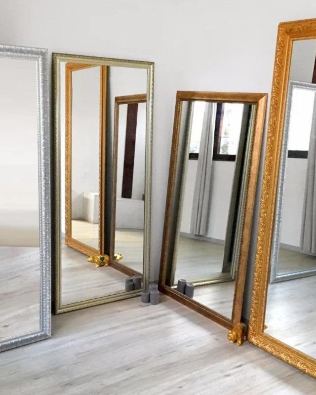 Four full length mirrors are lined up in a room