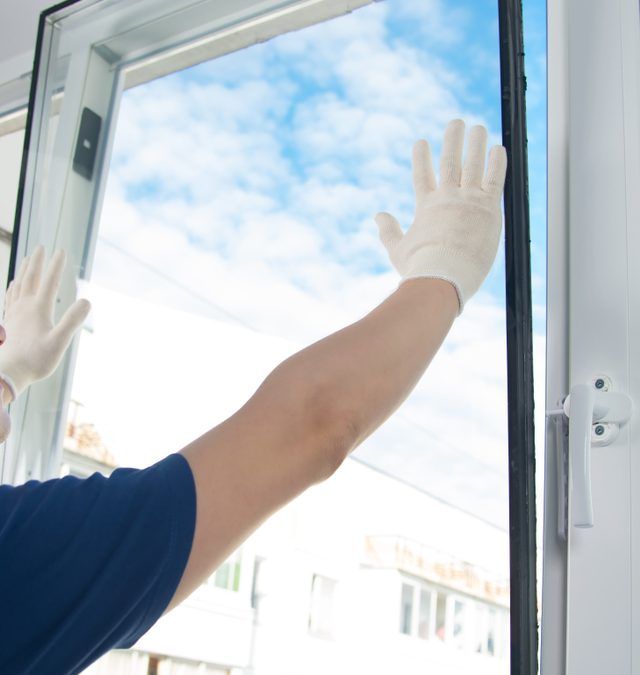 A man wearing white gloves is opening a window