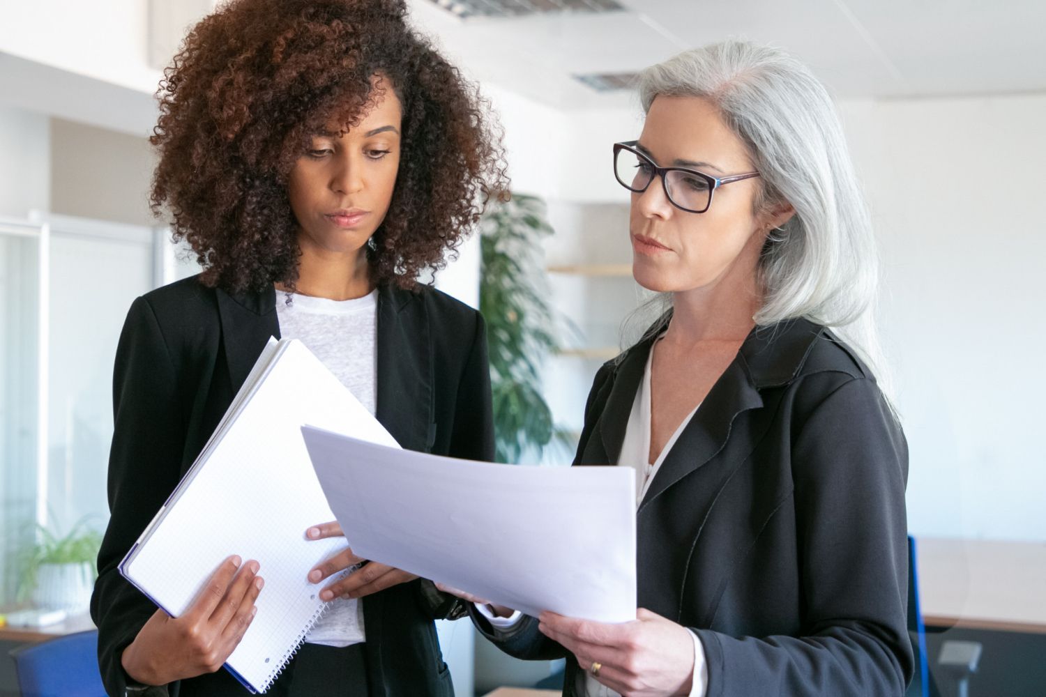 Two coworkers in a bright office reviewing documents together