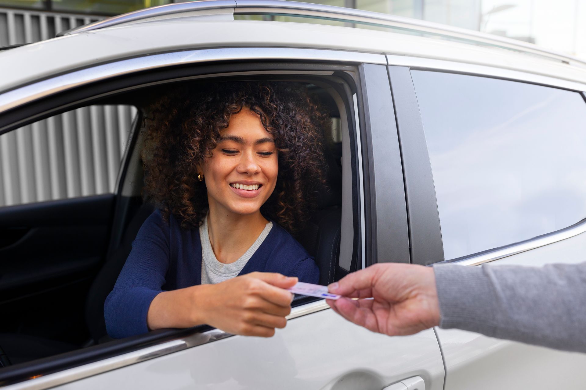 Woman smiles while taking car keys from a person through a car window