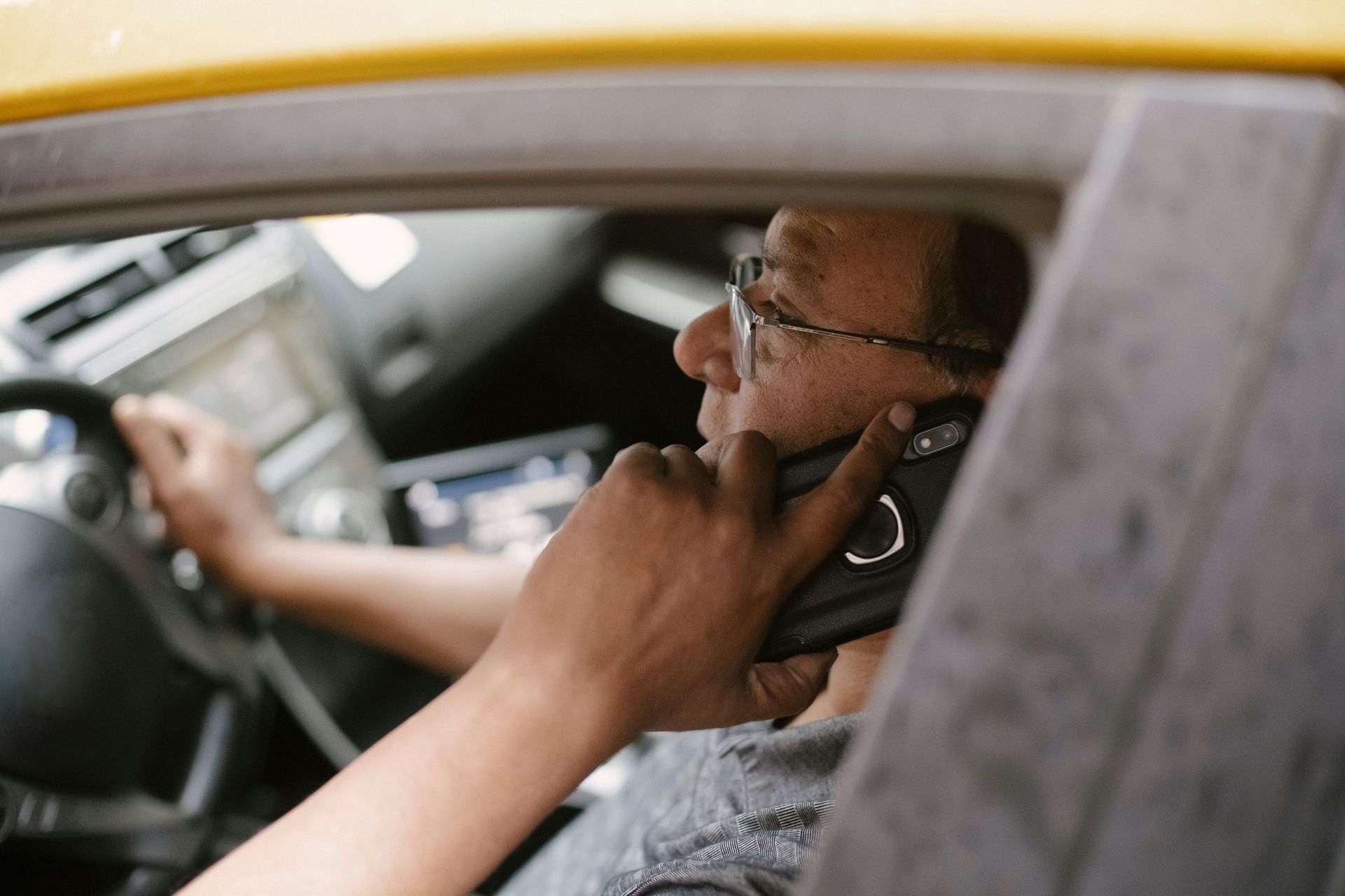Driver in car using a smartphone while steering, seen through the window